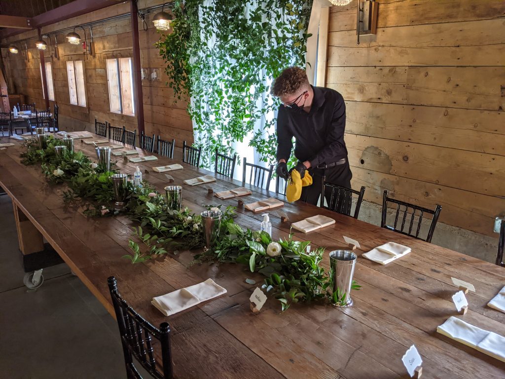 Catering during Covid. An Abritin employee sets out table settings at a wedding during Covid.